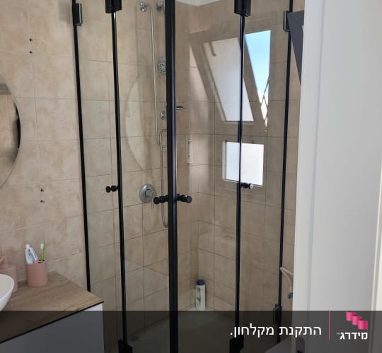 מקלחון זכוכית עם ראש מקלחת ובקבוק שמפו
